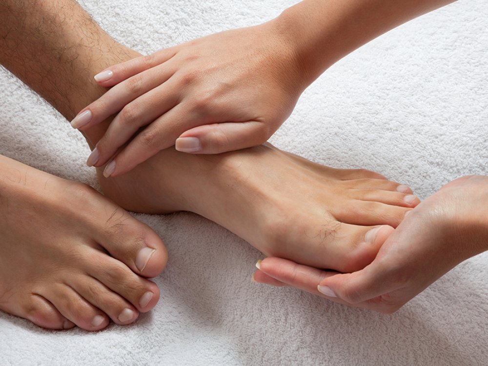 Wooden foot bath with flower petals and folded towels for a foot massage