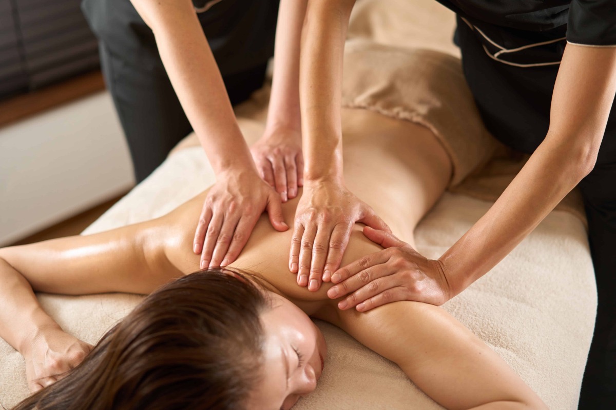 Two matching trays of rolled towels and oil prepared for a four hands massage